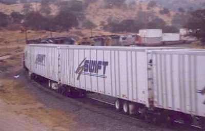 Swift RoadRailer passing Santa Fe stack train.
